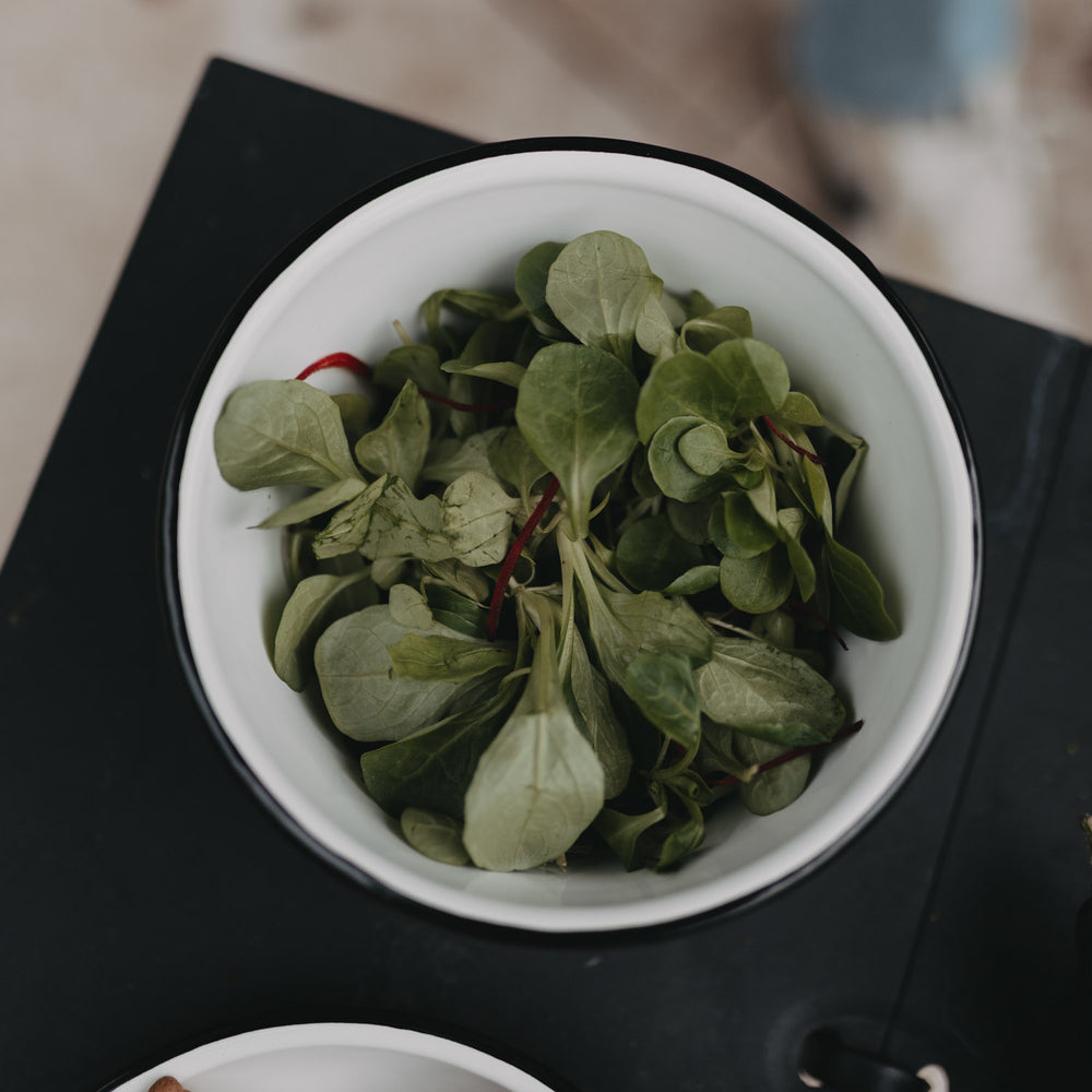 Emaille Schale Herz in Off-White von oben mit frischem Blattsalat, ideal für Garten oder Outdoor-Dining.
