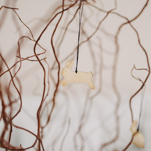 Goldener Metallanhänger Hase springend am Dekoast befestigt.