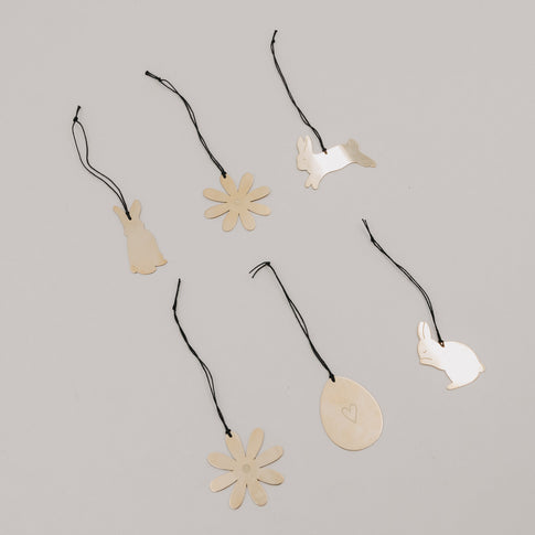 Goldene Metallanhänger Blume, Ei und Hasen auf hellem Hintergrund arrangiert.