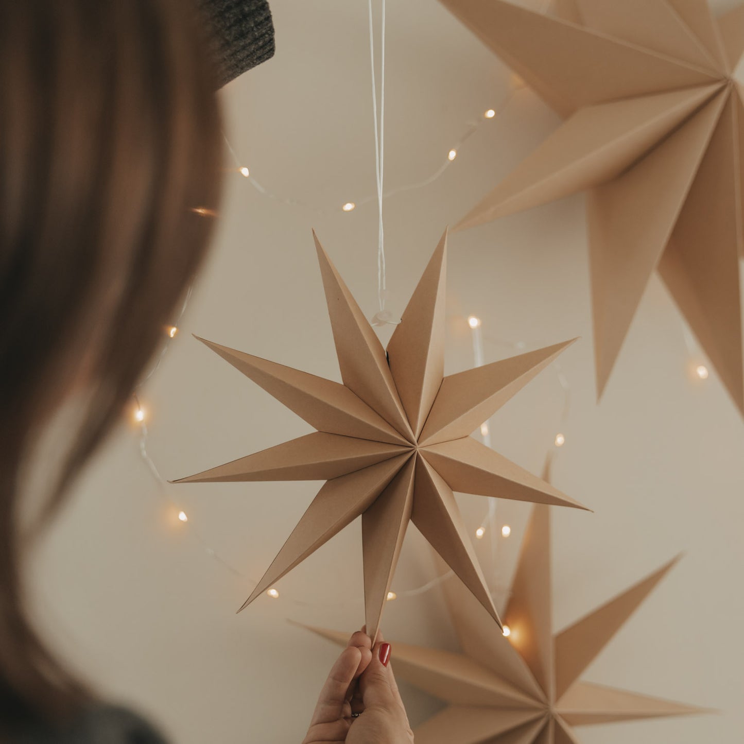 Brauner Papierstern mit gefalteter Struktur und Lichterkette als stilvolle Weihnachtsdekoration