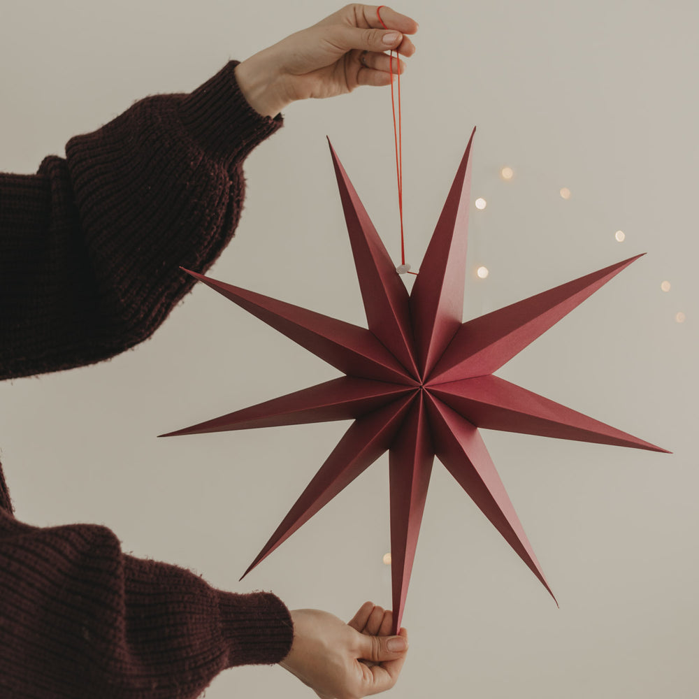 Großer roter Papierstern mit langen Spitzen und roter Aufhängung als festliche Weihnachtsdeko