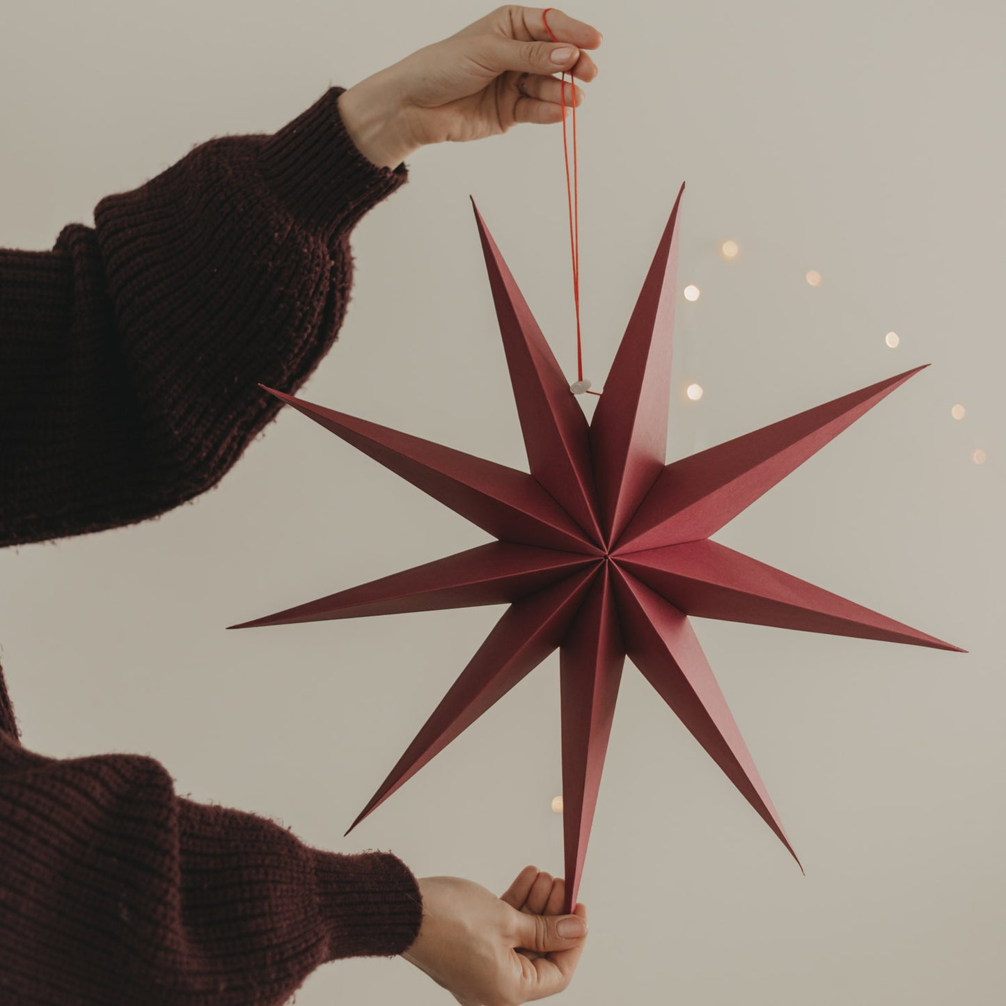 Großer roter Papierstern mit langen Spitzen und roter Aufhängung als festliche Weihnachtsdeko