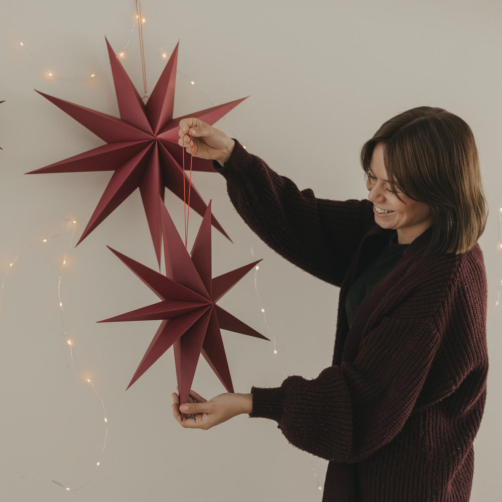Rote Papiersterne in verschiedenen Größen mit Lichterkette als moderne Weihnachtsdekoration