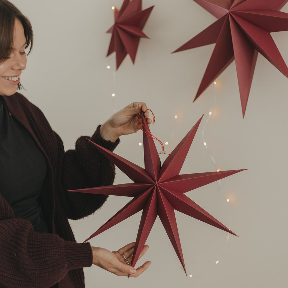 Roter Papierstern mit langen Spitzen und Aufhängung als stilvolle Weihnachtsdekoration