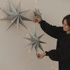 Graue Papiersterne in verschiedenen Größen mit Lichterkette als minimalistische Weihnachtsdekoration