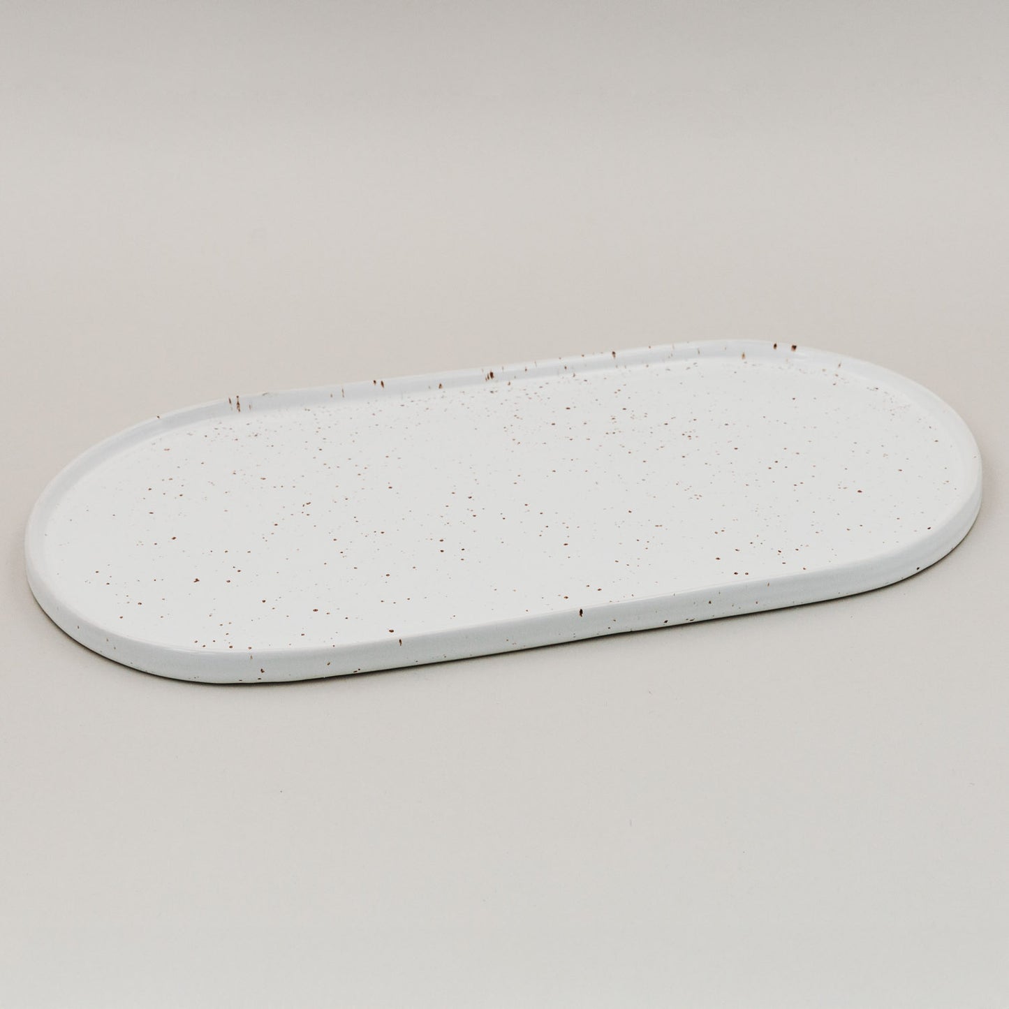 Weiße ovale Servierplatte Calma groß mit Sprenkelmuster auf hellem Hintergrund