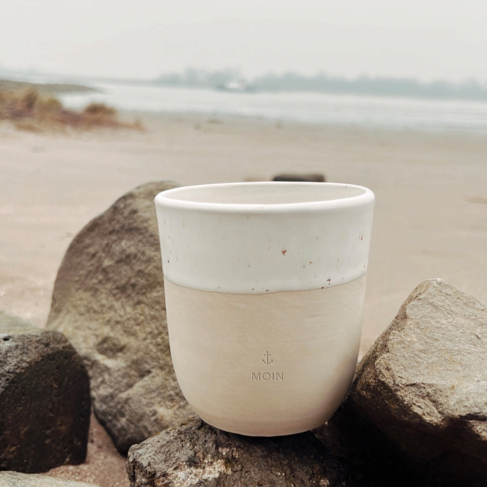 Minimalistischer Steingutbecher Moin zwischen Steinen am Strand dekoriert