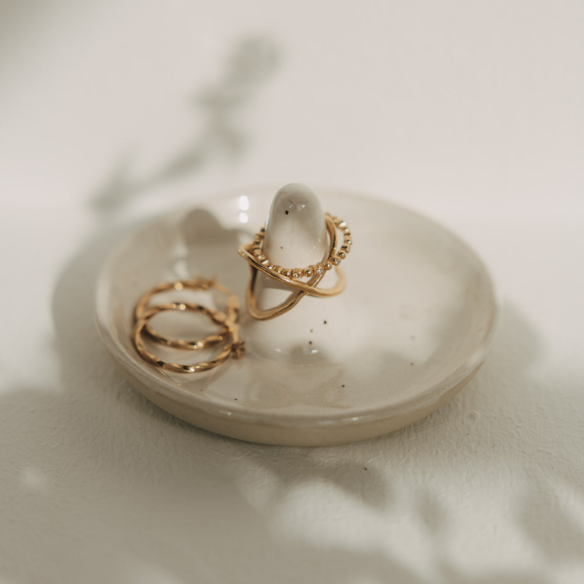 Schmuckablage aus Keramik mit Ringhalter und goldenen Ringen