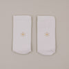 Minimalistische Produktansicht weißer Socken mit kleinem Daisy-Motiv auf hellem Hintergrund