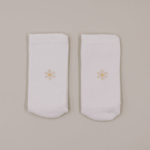 Minimalistische Produktansicht weißer Socken mit kleinem Daisy-Motiv auf hellem Hintergrund