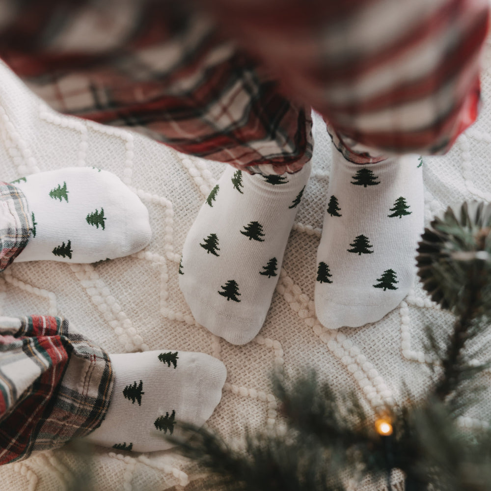 Weiße Eulenschnitt Socken mit grünen Tannen für Erwachsene und Kinder in weihnachtlicher Atmosphäre.
