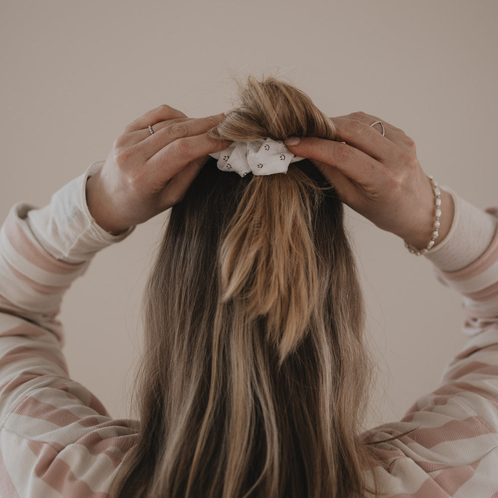 Hände stylen Dutt mit weißem Scrunchie mit Smiley-Muster