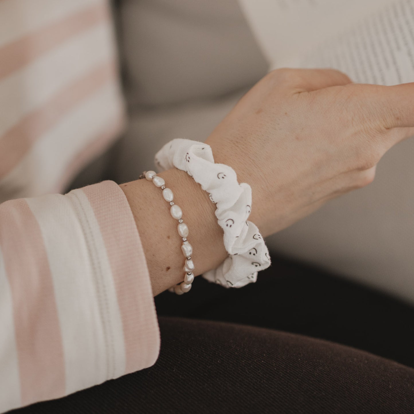 Detail Scrunchie mit Smiley-Muster am Handgelenk beim Lesen