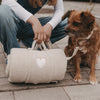 Person mit Hund und tragbarer Hundedecke in Creme unterwegs