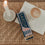 Streichholzschachtel „Sardinen“ in Blau und Rosa mit langen Streichhölzern neben Kerze und Kaffee