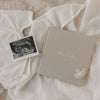 Schwangerschaftstagebuch „Kleines Wunder“ mit Ultraschallbild und Babybody auf weichen Textilien.