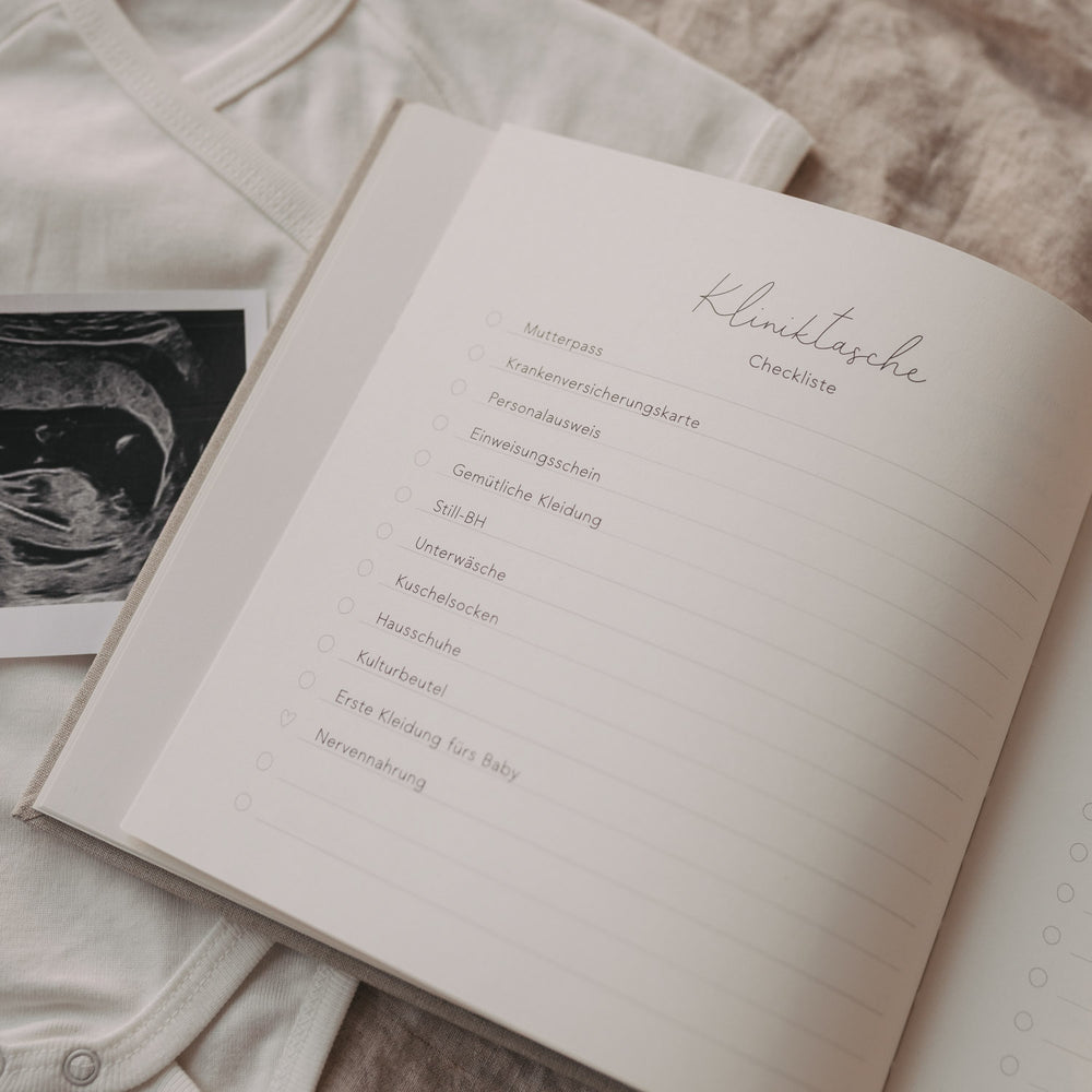 Offene Checkliste für die Kliniktasche im Schwangerschaftstagebuch neben Ultraschallbild.