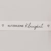 Nahaufnahme des Baumwollbands mit Aufdruck „Klitzekleine Kleinigkeit“ und kleinen Herzsymbolen