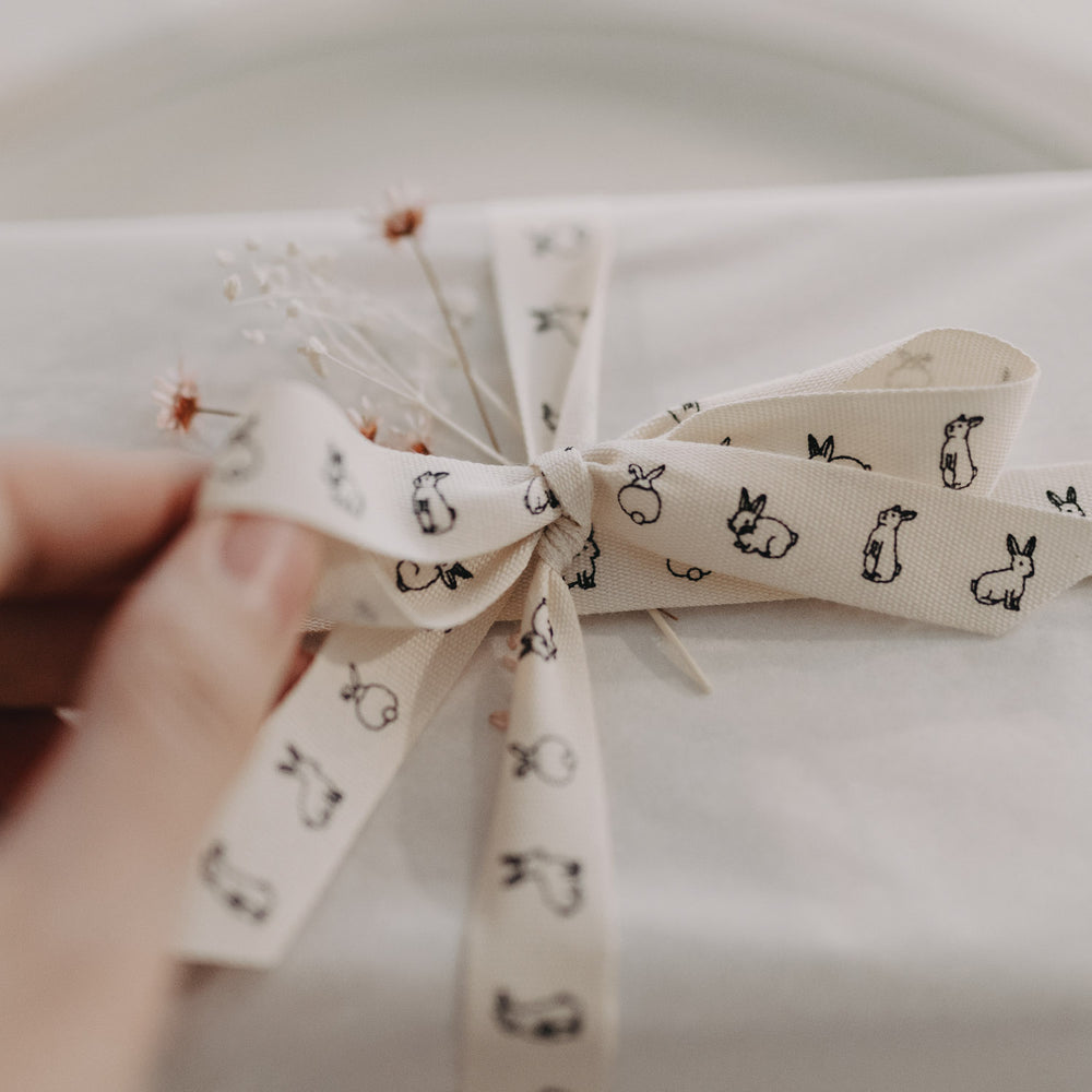 Nahaufnahme einer Schleife aus Kaninchen-Geschenkband mit feinen Trockenblumen.