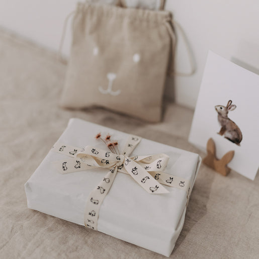 Eingepacktes Geschenk mit Kaninchen-Geschenkband vor Beutel und Hasenkarte.