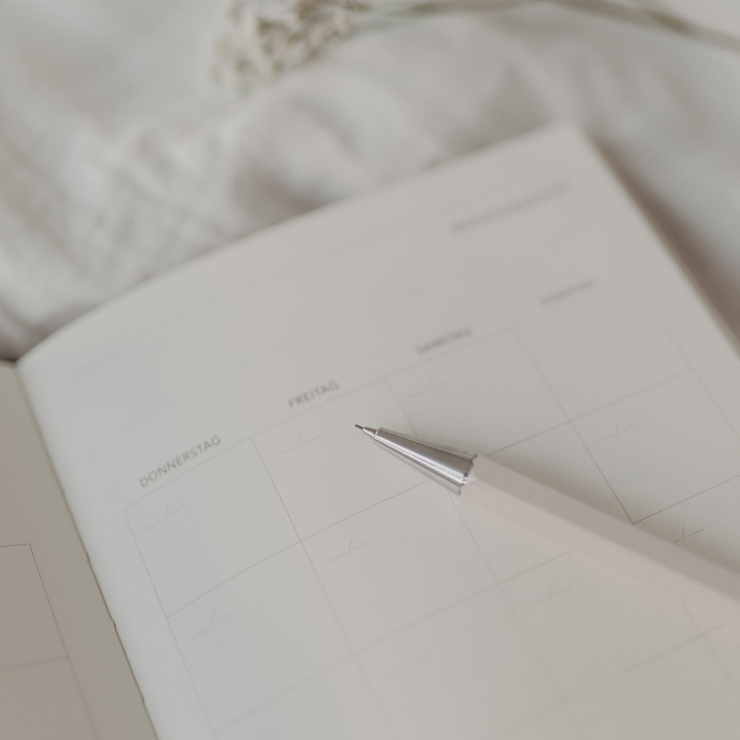 Druckbleistift Creme liegend auf einem offenen Kalender in heller Umgebung.