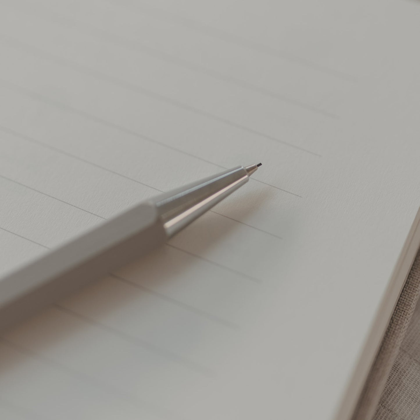 Nahaufnahme der silbernen Spitze des grauen Druckbleistifts auf linierten Seiten.