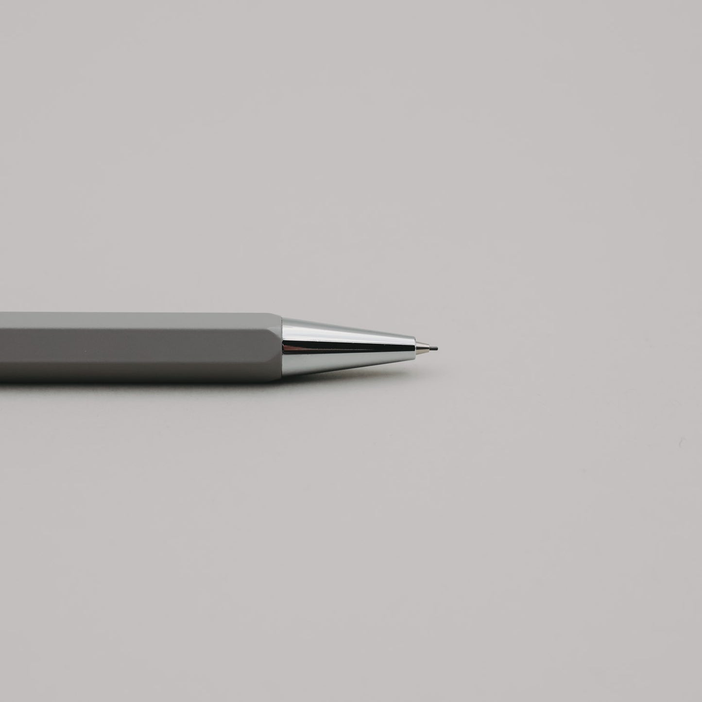 Grauer Druckbleistift mit silberner Spitze auf hellem Hintergrund, minimalistisch und elegant.