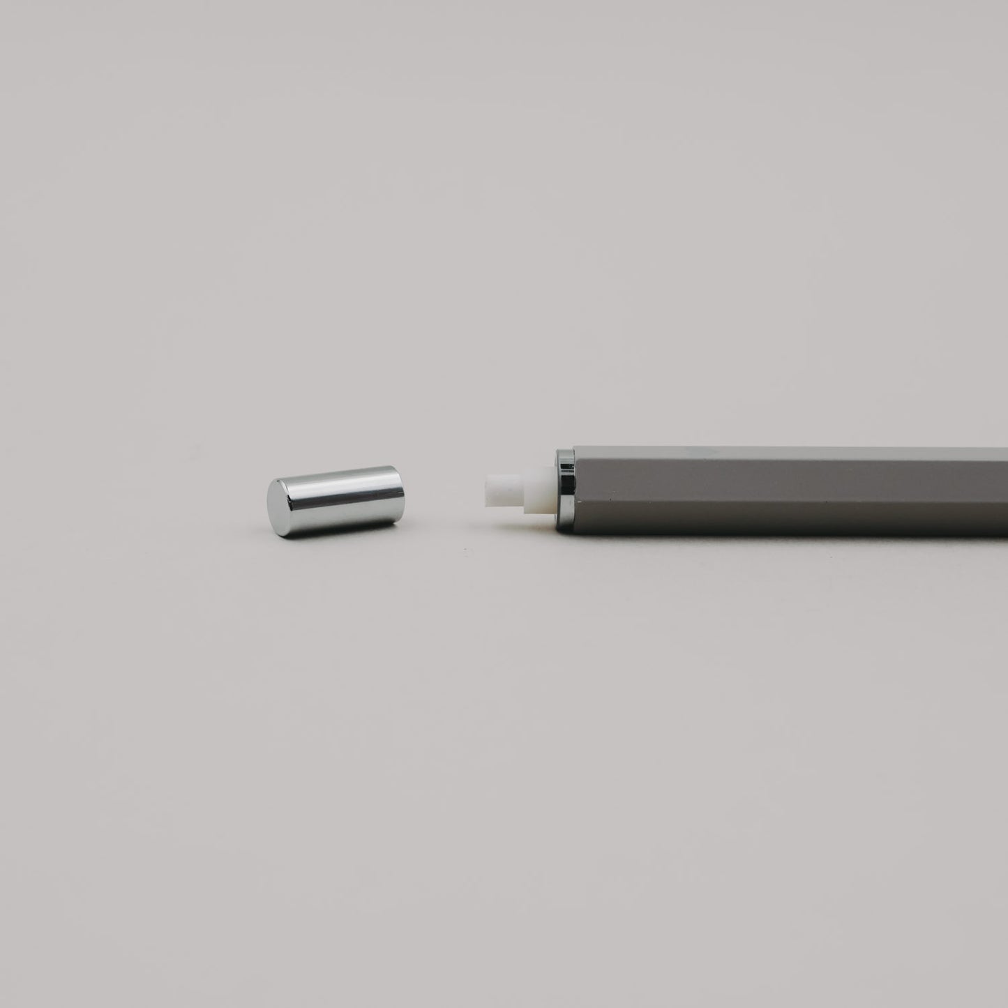 Grauer Druckbleistift mit abgenommener Kappe, sichtbar integriertem Radiergummi im Drücker.