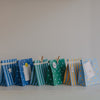 Geschenktüten aus Papier in Blau, Grün und Gelb mit Punkten und Streifen, dekorativ aufgereiht