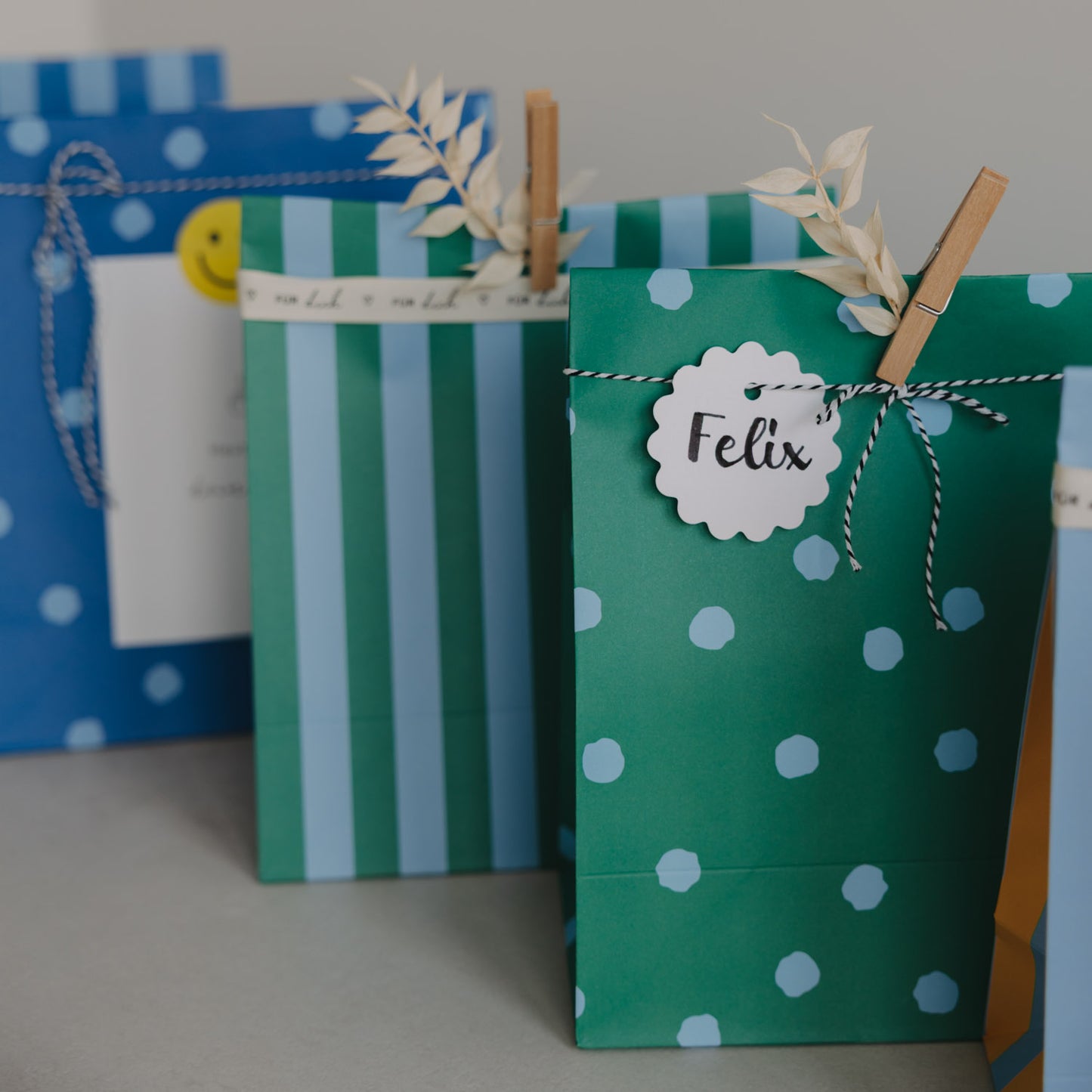 Detailansicht grüne Geschenktüte aus Papier mit Punkten, Namensanhänger und Kordel