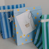 Hellblaue Papier-Geschenktüte mit gelben Punkten und Geschenkanhänger mit Cupcake