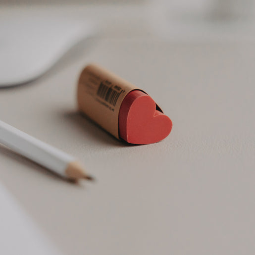 Roter Radiergummi Herzform in Papierhülle auf Schreibtisch