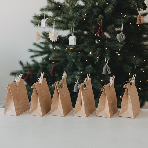 Verschiedene weihnachtliche Geschenktüten aus Kraftpapier mit Klammern und Trockenblumen