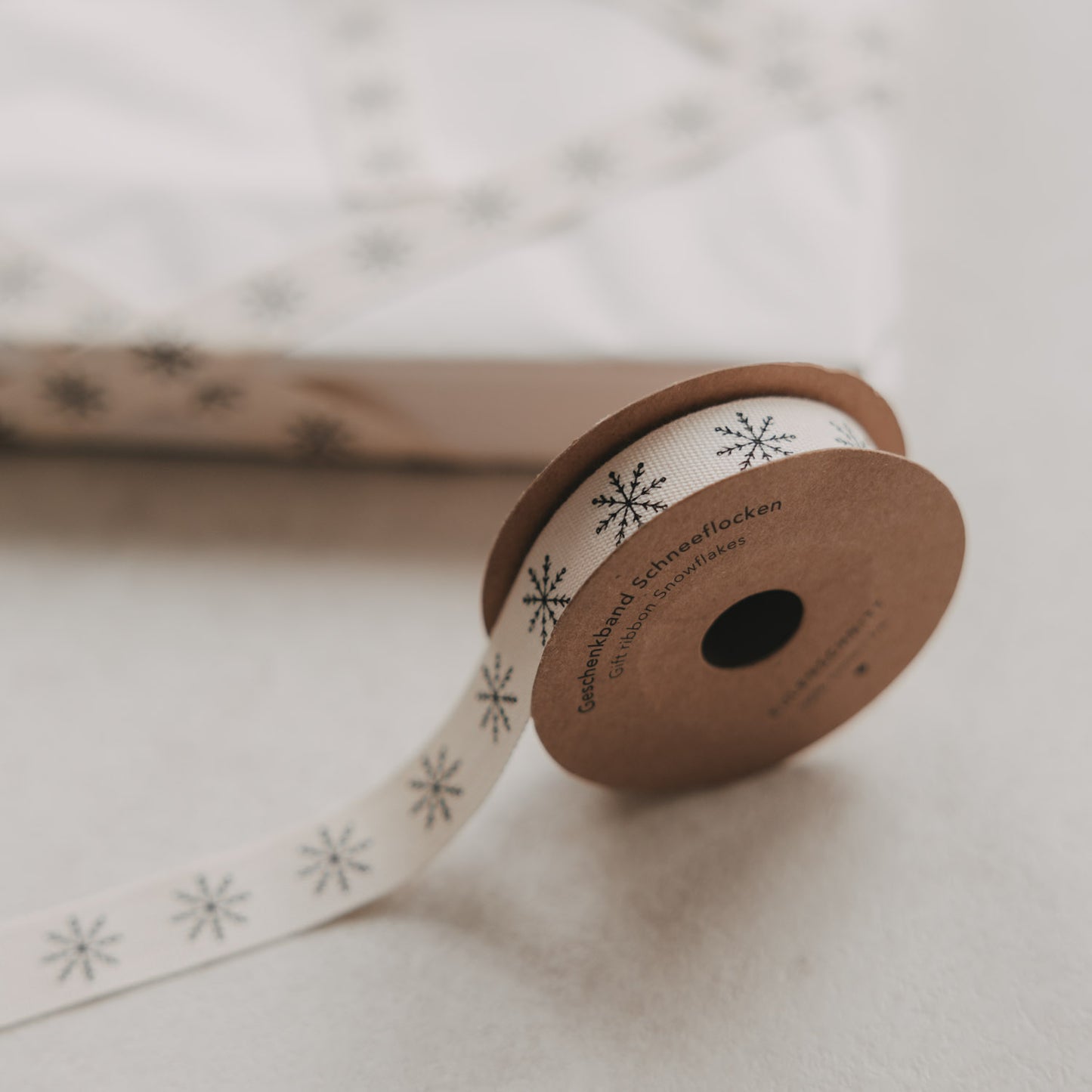Eulenschnitt Geschenkband Schneeflocken in Beige auf Rolle mit schwarzen Schneeflocken