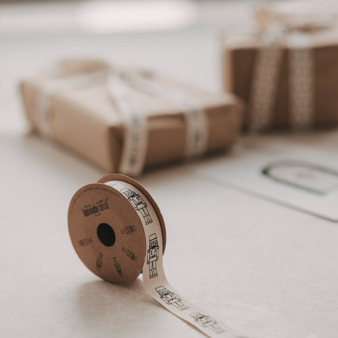 Geschenkband mit Nussknacker-Motiv auf Rolle vor weihnachtlich verpackten Geschenken