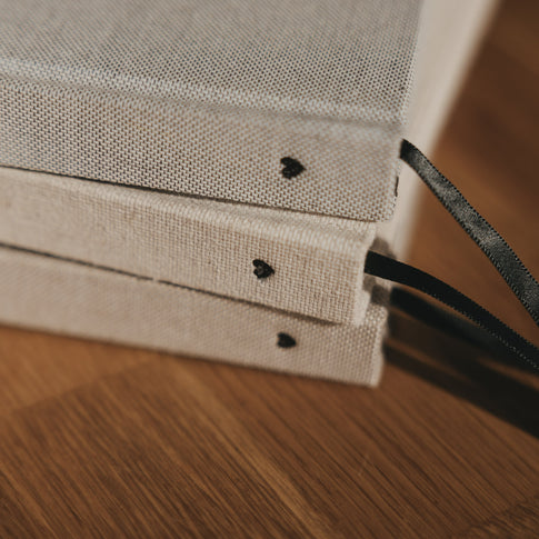 Drei A5 Notizbücher mit Leineneinband, schwarzem Herz am Buchrücken und schwarzem Leseband
