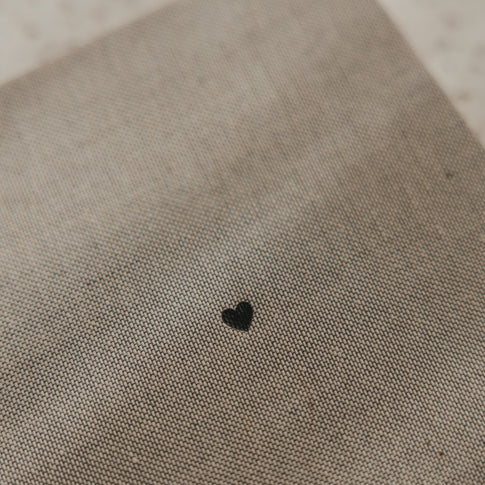 Detail des grau beigen Stoffeinbands vom karierten A5 Notizbuch mit kleinem schwarzem Herz