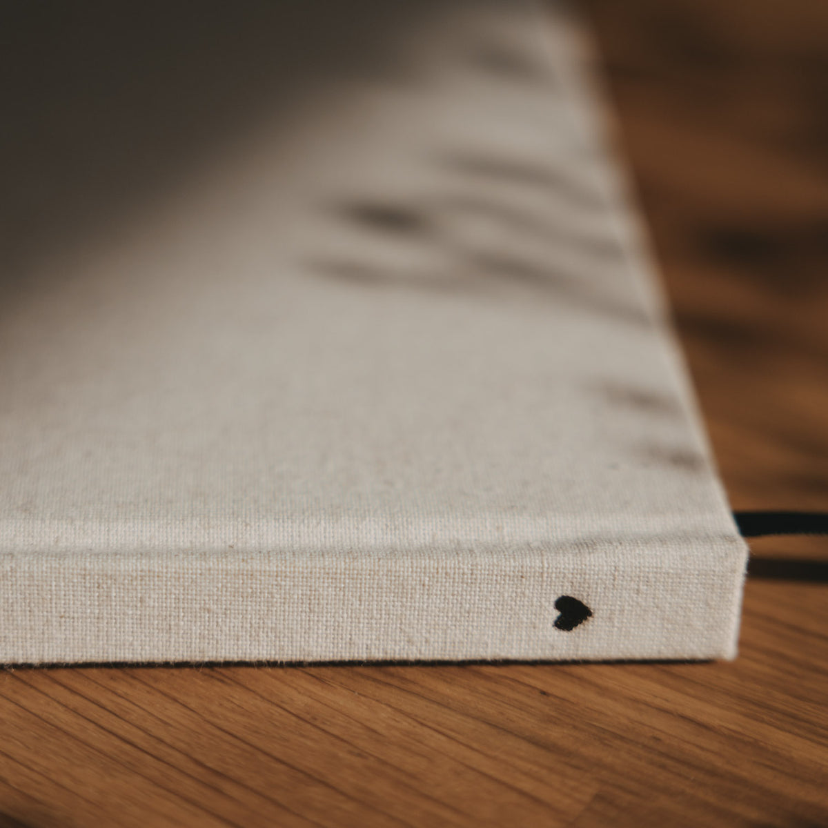 Detailansicht des beigen Leineneinbands mit kleinem schwarzem Herz auf dem Buchrücken